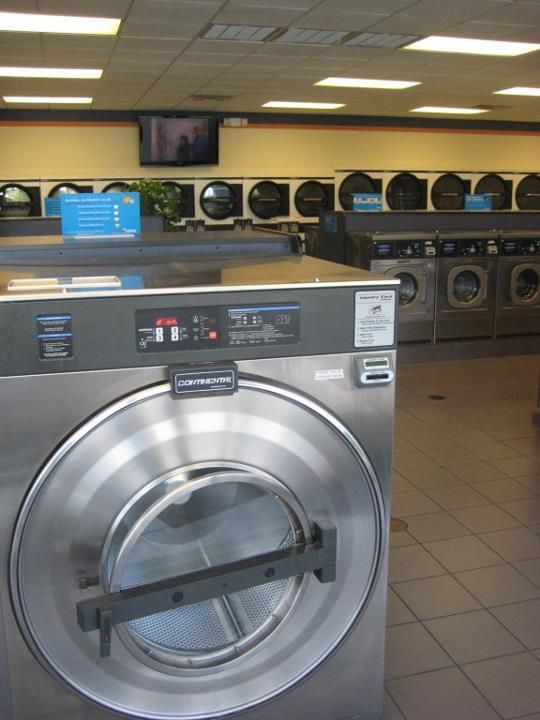 A washer and dryer in a laundromat with the door open