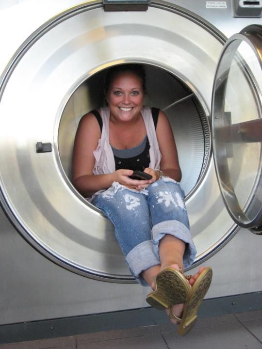 A woman is sitting in a washing machine and smiling