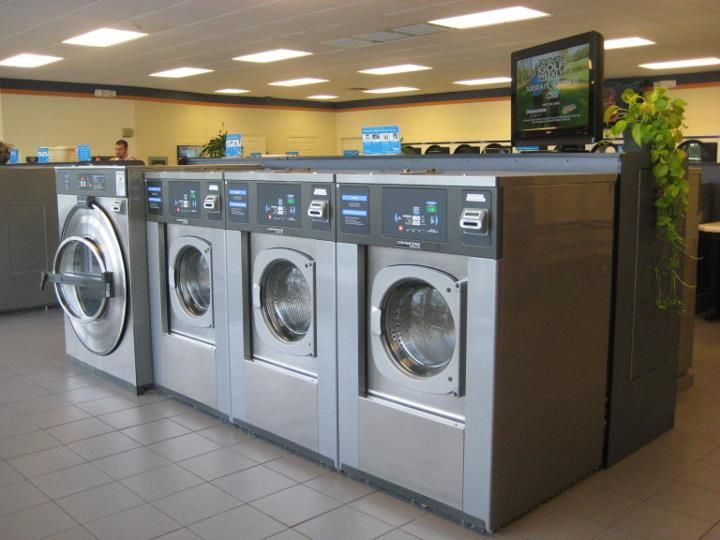 A woman is sitting in a washing machine with the door open