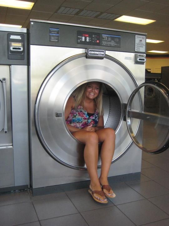 A woman is sitting in a washing machine with the door open