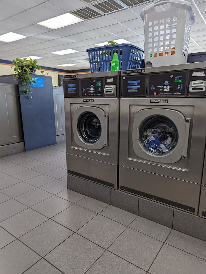 A laundromat with two washing machines and a basket on top of one of them.
