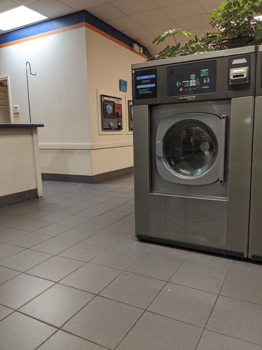 A washing machine is sitting in a laundromat next to a counter.