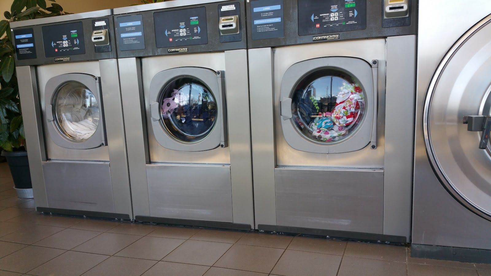 A row of washing machines are lined up in a laundromat.