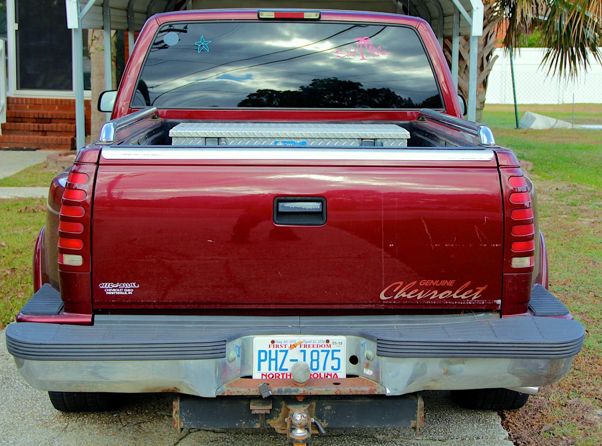 A rear view of a dark red Chevrolet pickup truck parked on a paved driveway with a Florida license plate visible.