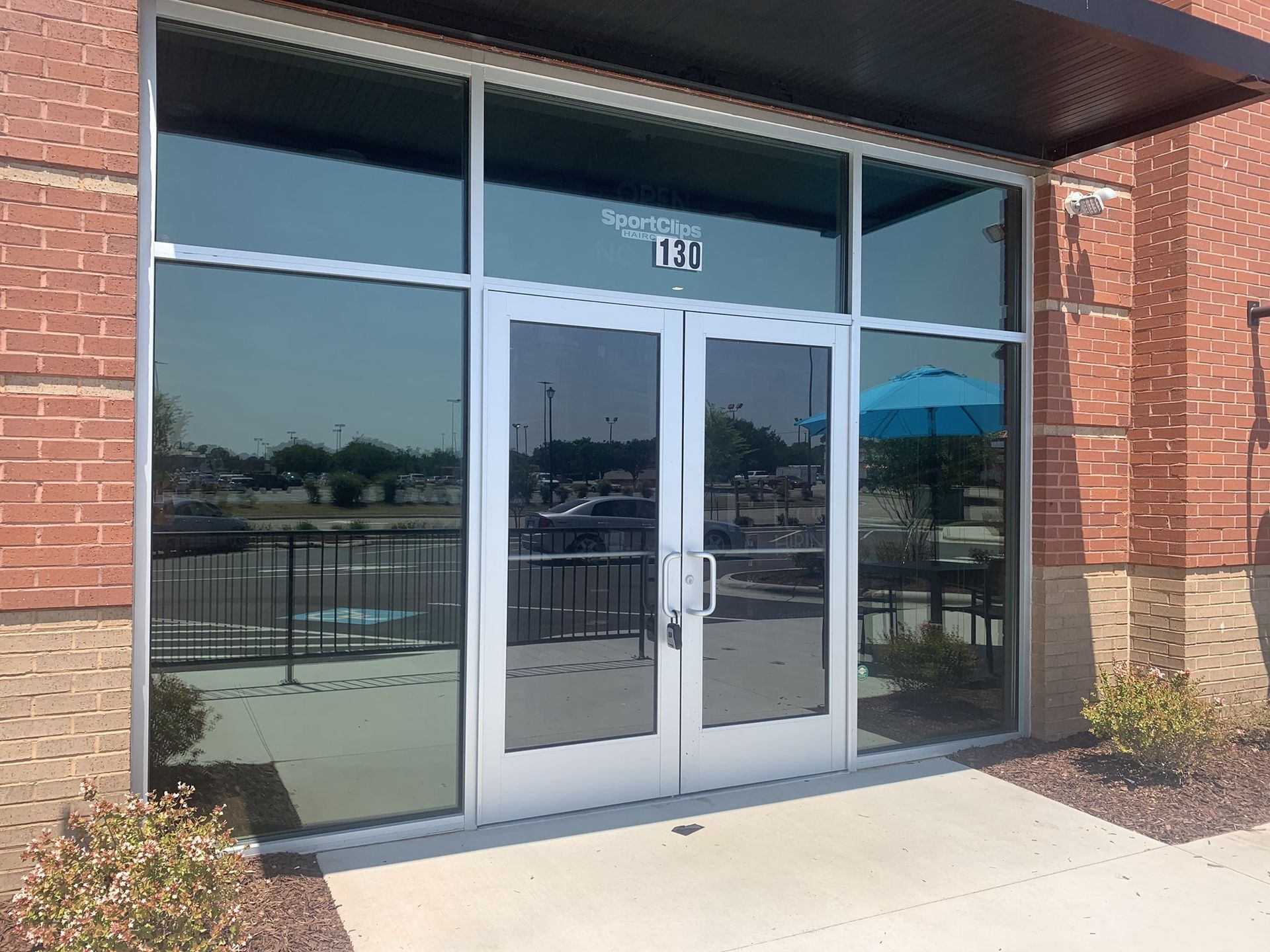 Double glass doors at the entrance of a brick building with a metal awning and a visible suite number, 101.