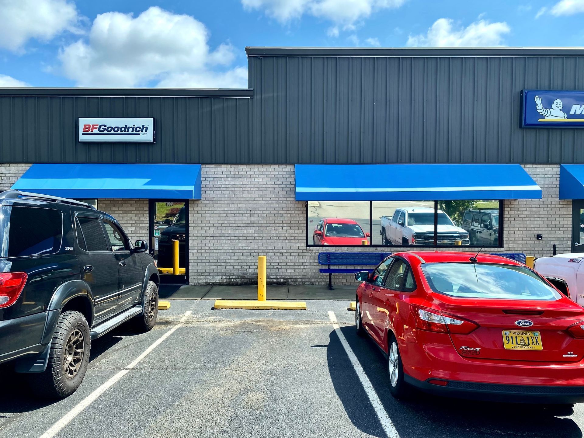 A parking lot in front of a brick commercial building with blue awnings and a BFGoodrich sign.