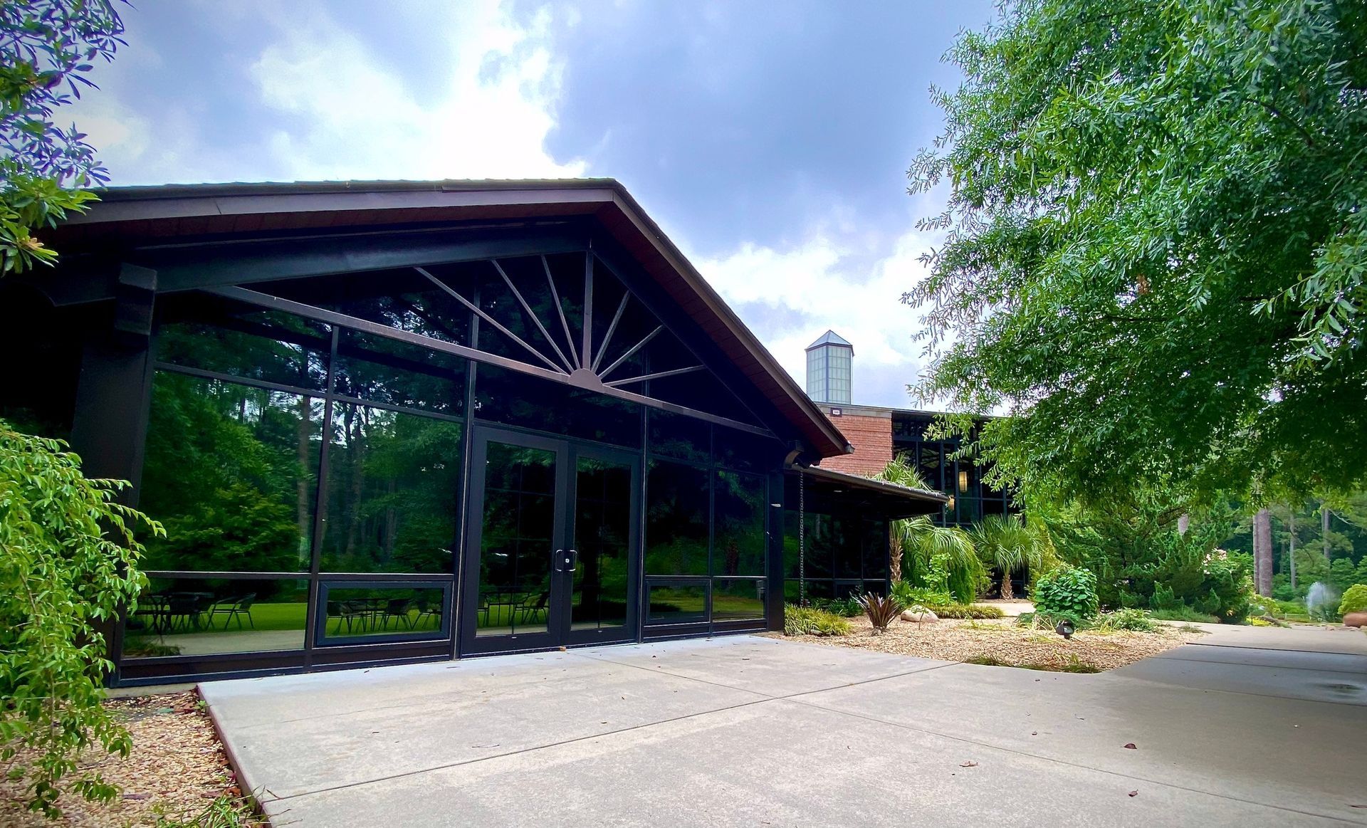 A large lodge-style building with dark wood beams, floor-to-ceiling glass walls, and a sunburst architectural detail.