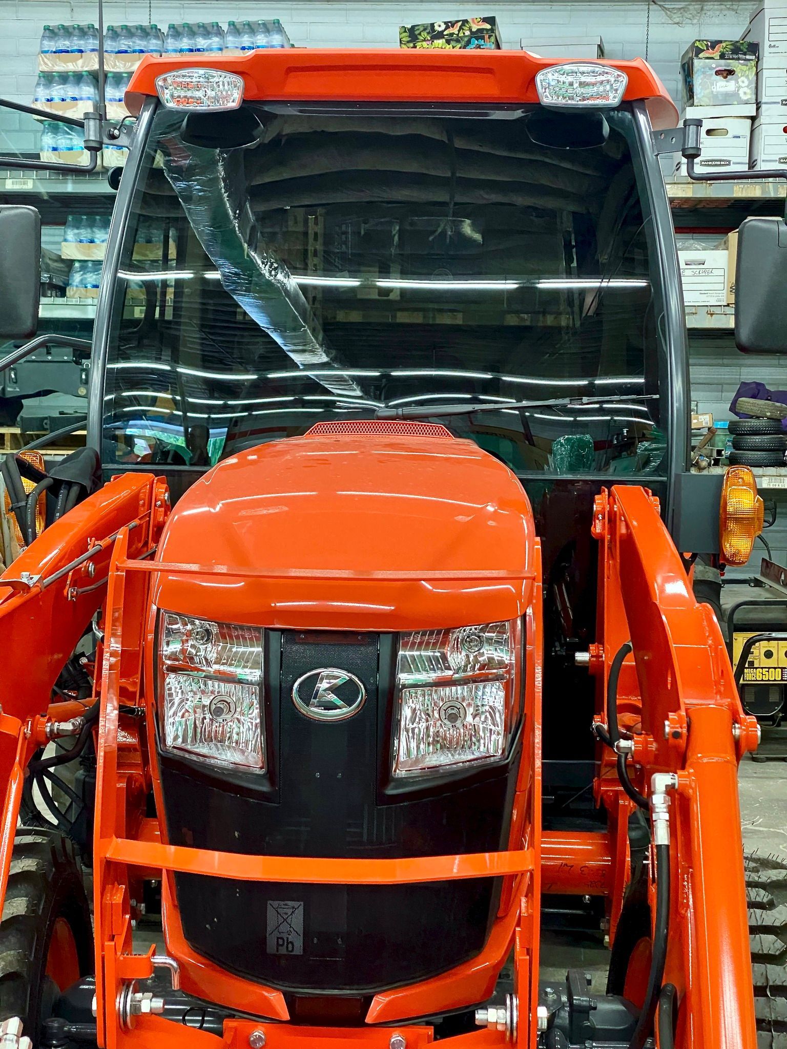 A bright orange tractor with a front-end loader parked indoors.