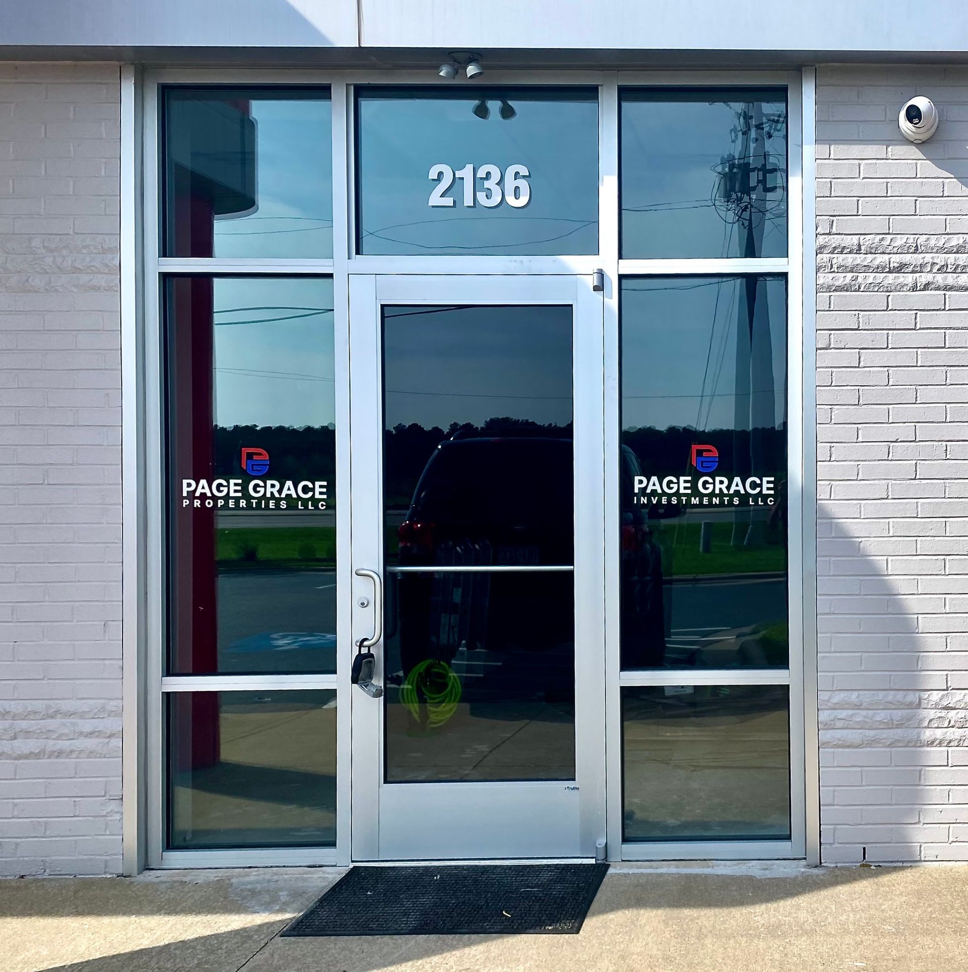 A glass storefront entrance marked 2136 with a Page Grace Plumbing LLC logo on the windows.