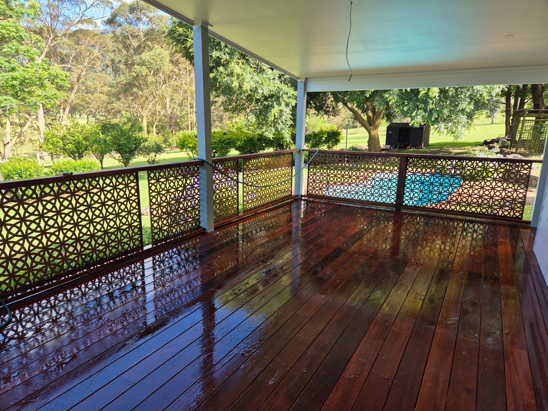 Wooden deck with decorative railing overlooking a green landscape.
