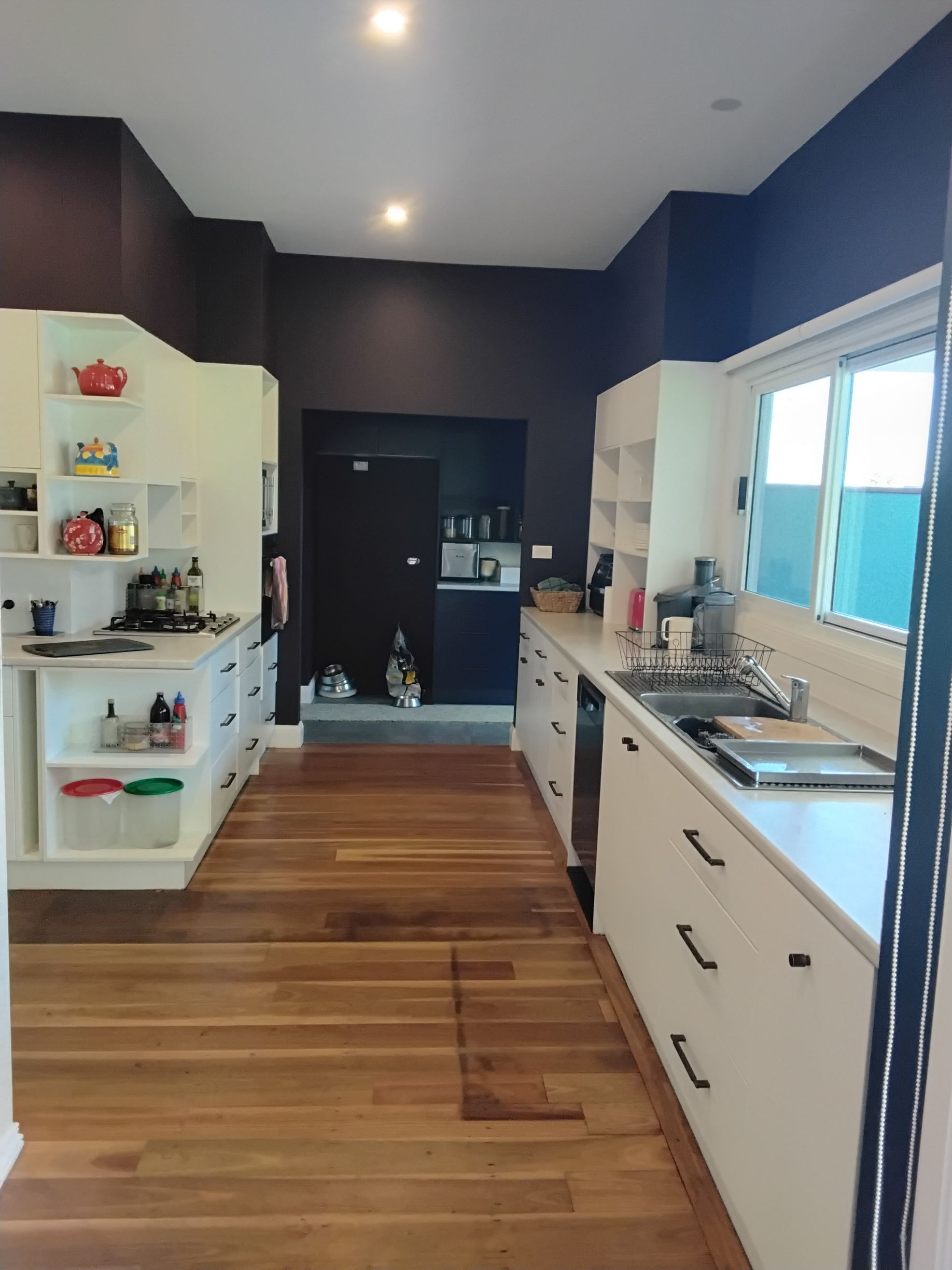 Kitchen with white cabinets, dark walls, and wooden floor.