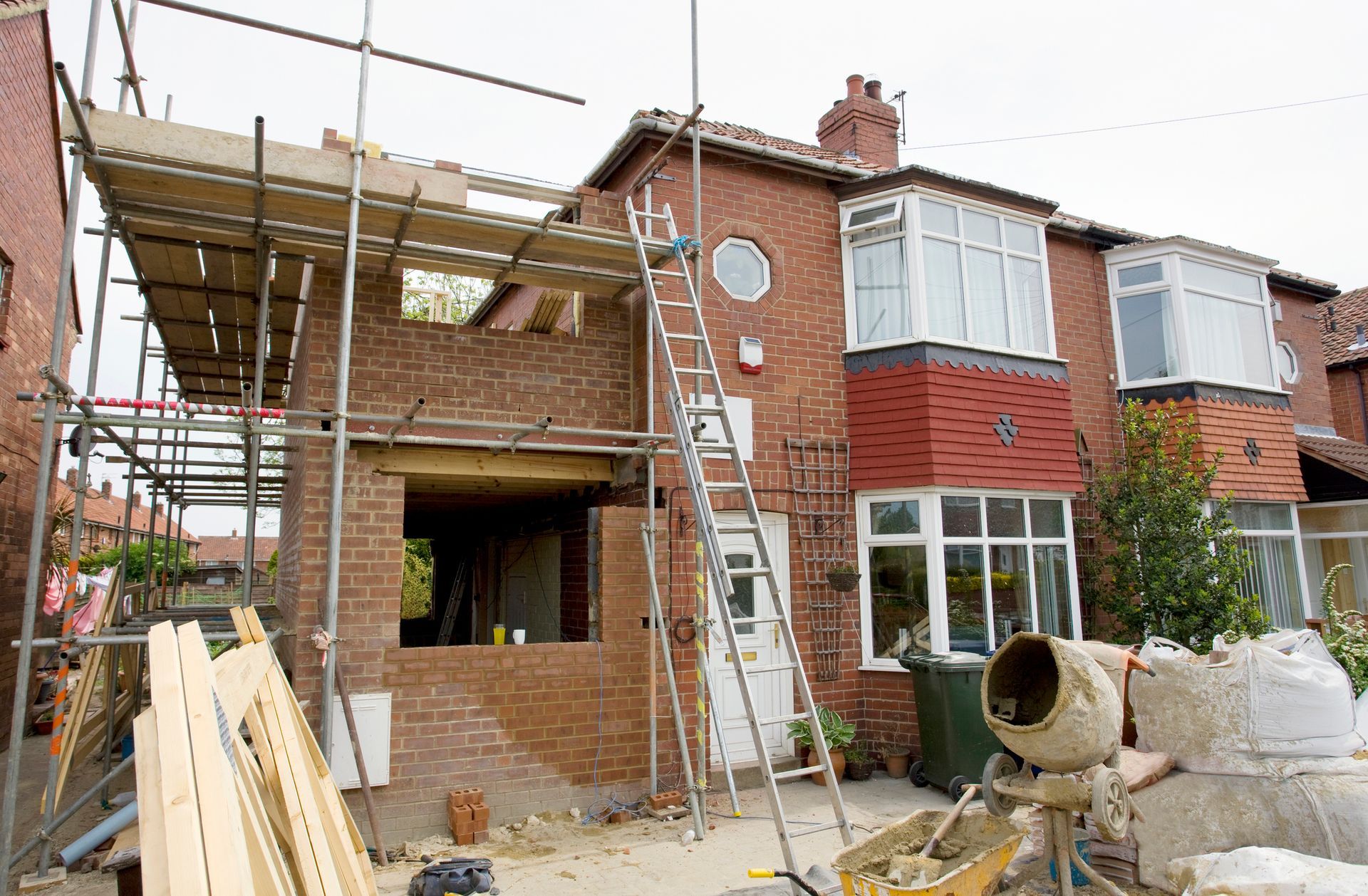 House extension under construction with scaffolding, brickwork visible.