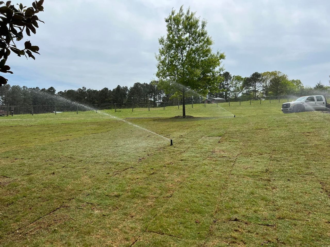 A sprinkler is spraying water on a lush green field.