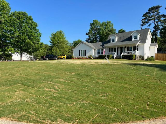 A white house with a large lawn in front of it