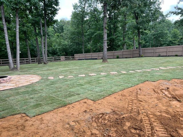 A backyard with a fence and a lot of grass and dirt.