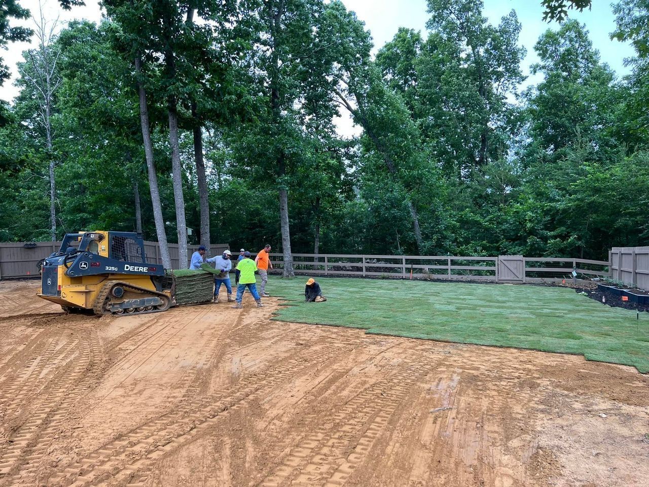A group of people are working on a field with a bulldozer.