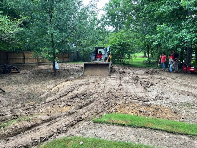 A bulldozer is moving dirt in a backyard.