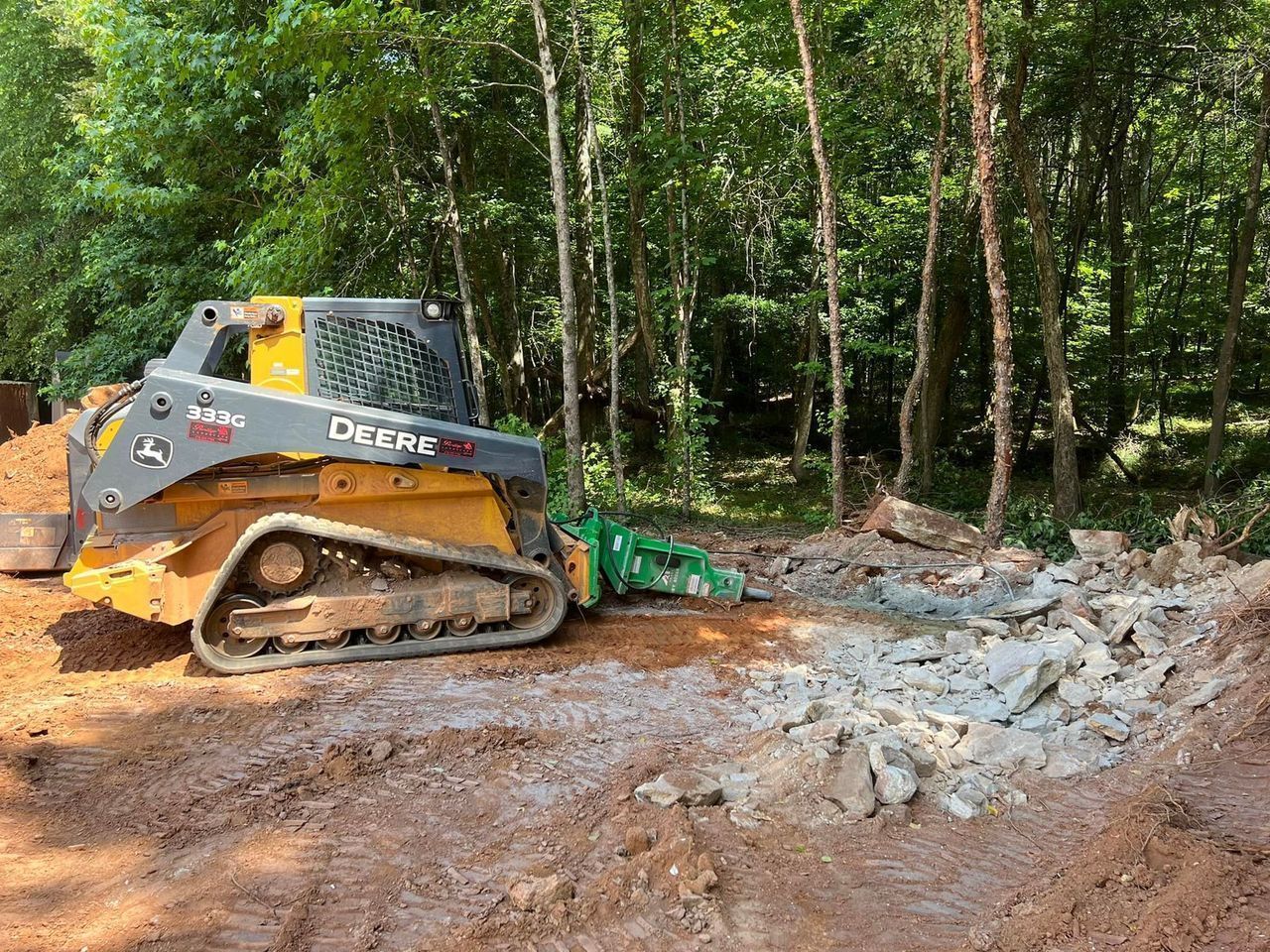 A bulldozer is sitting on top of a pile of dirt in the woods.