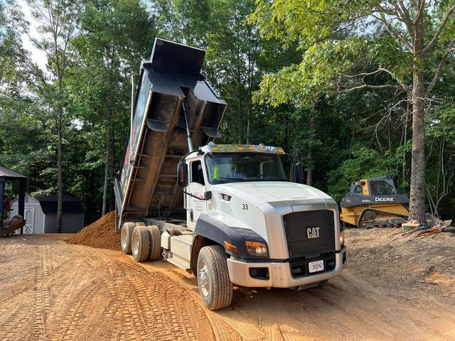 A dump truck is sitting on top of a dirt road.