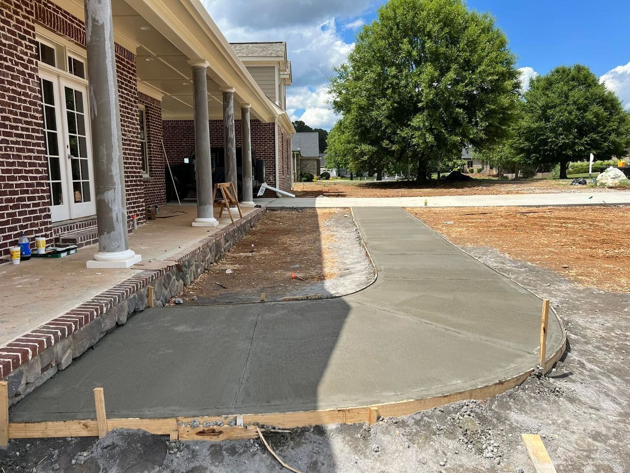 A concrete walkway is being built in front of a brick house.