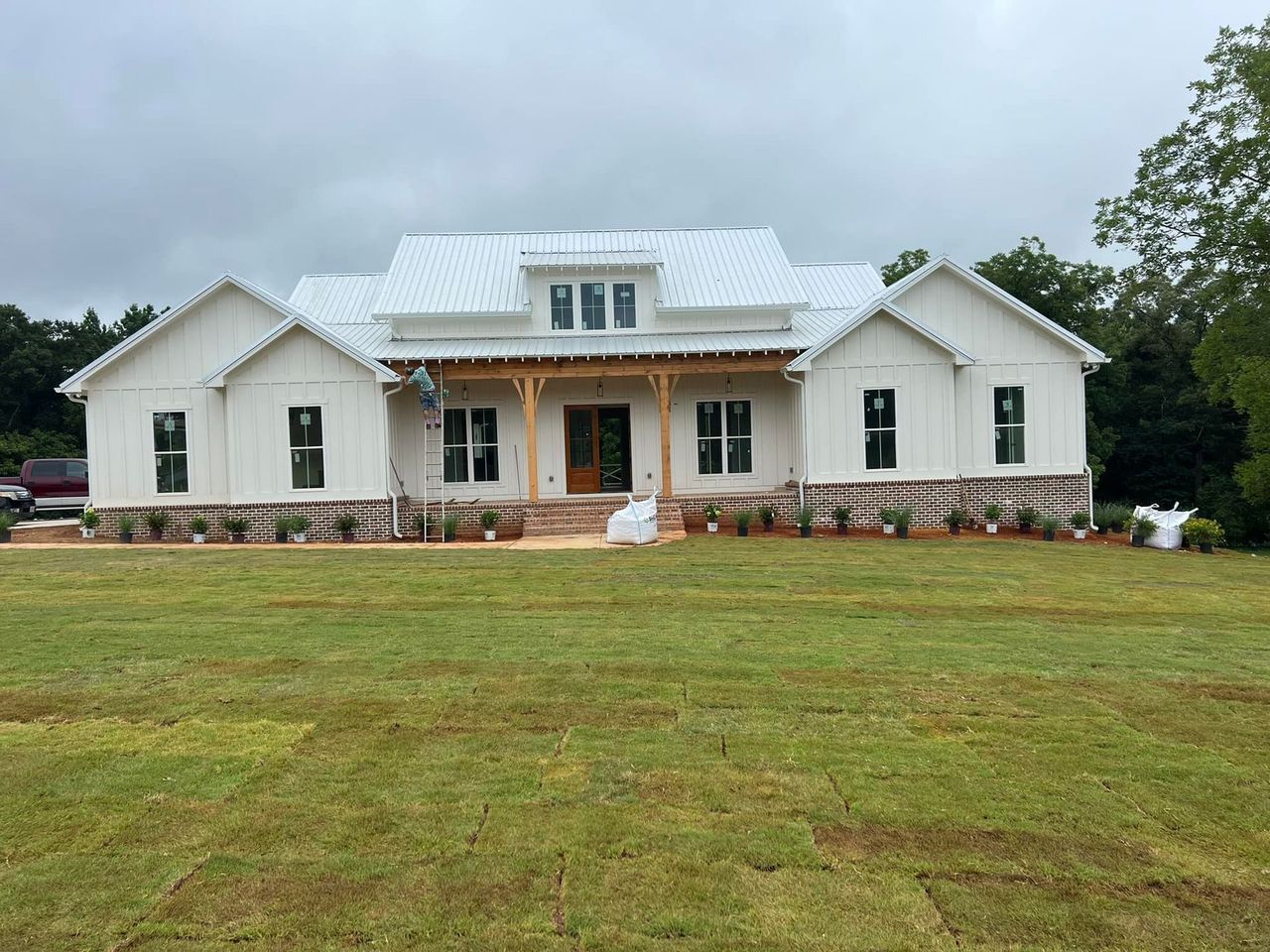A large white house is sitting in the middle of a lush green field.