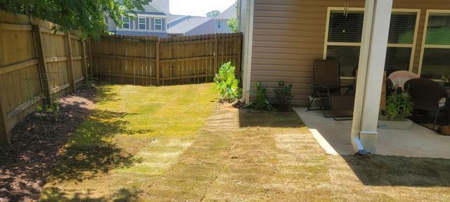 A backyard with a wooden fence and a patio.