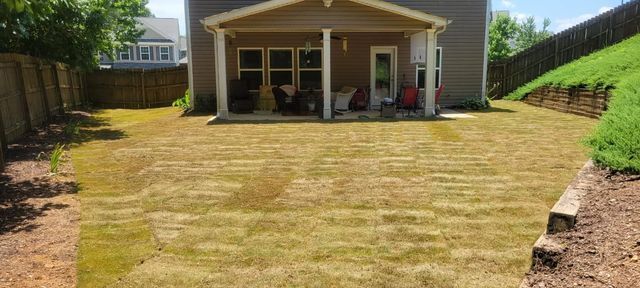 A house with a porch and a large lawn in front of it.
