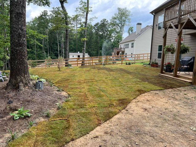 A backyard with a lot of grass and a house in the background.