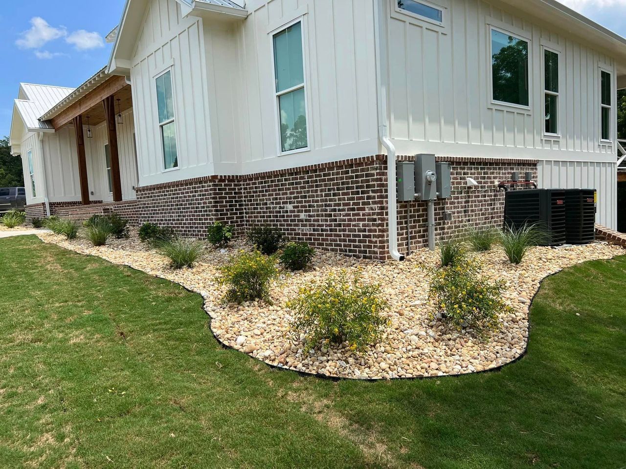 A white house with a lot of plants in front of it.