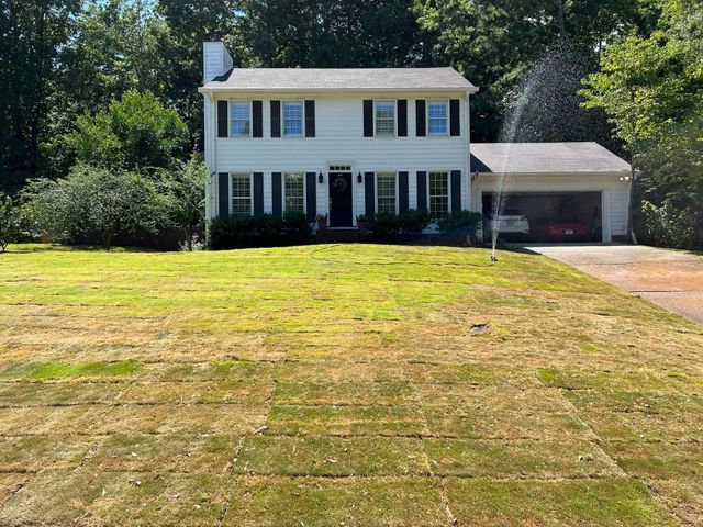 A white house with a large lawn in front of it