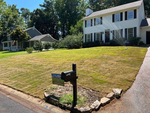 A white house with a large lawn and a mailbox in front of it.