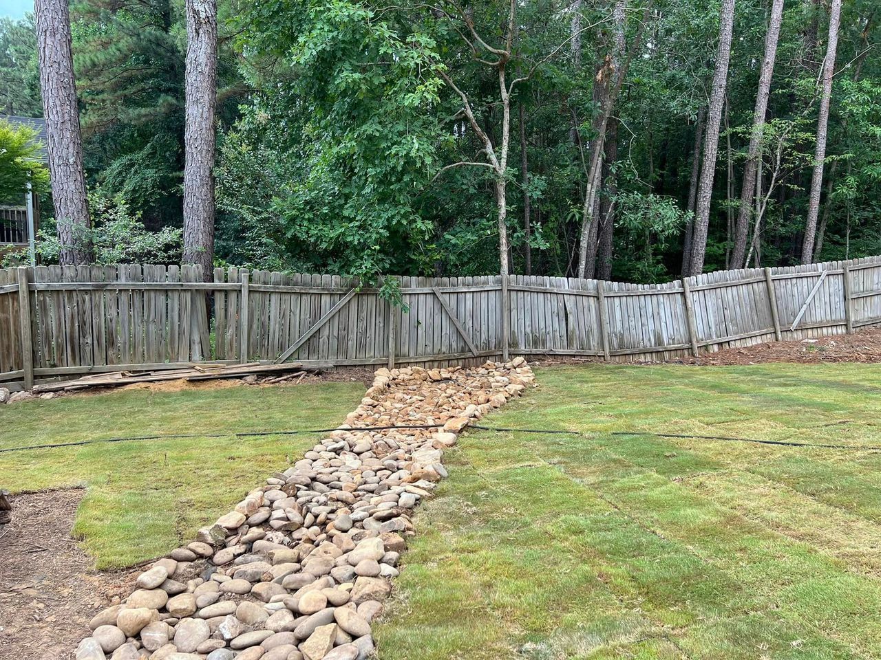 A stone path leading to a wooden fence in a backyard.