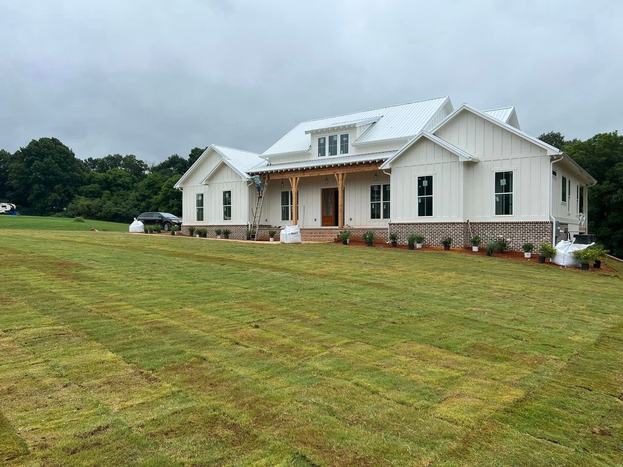 A white house is sitting on top of a lush green field.