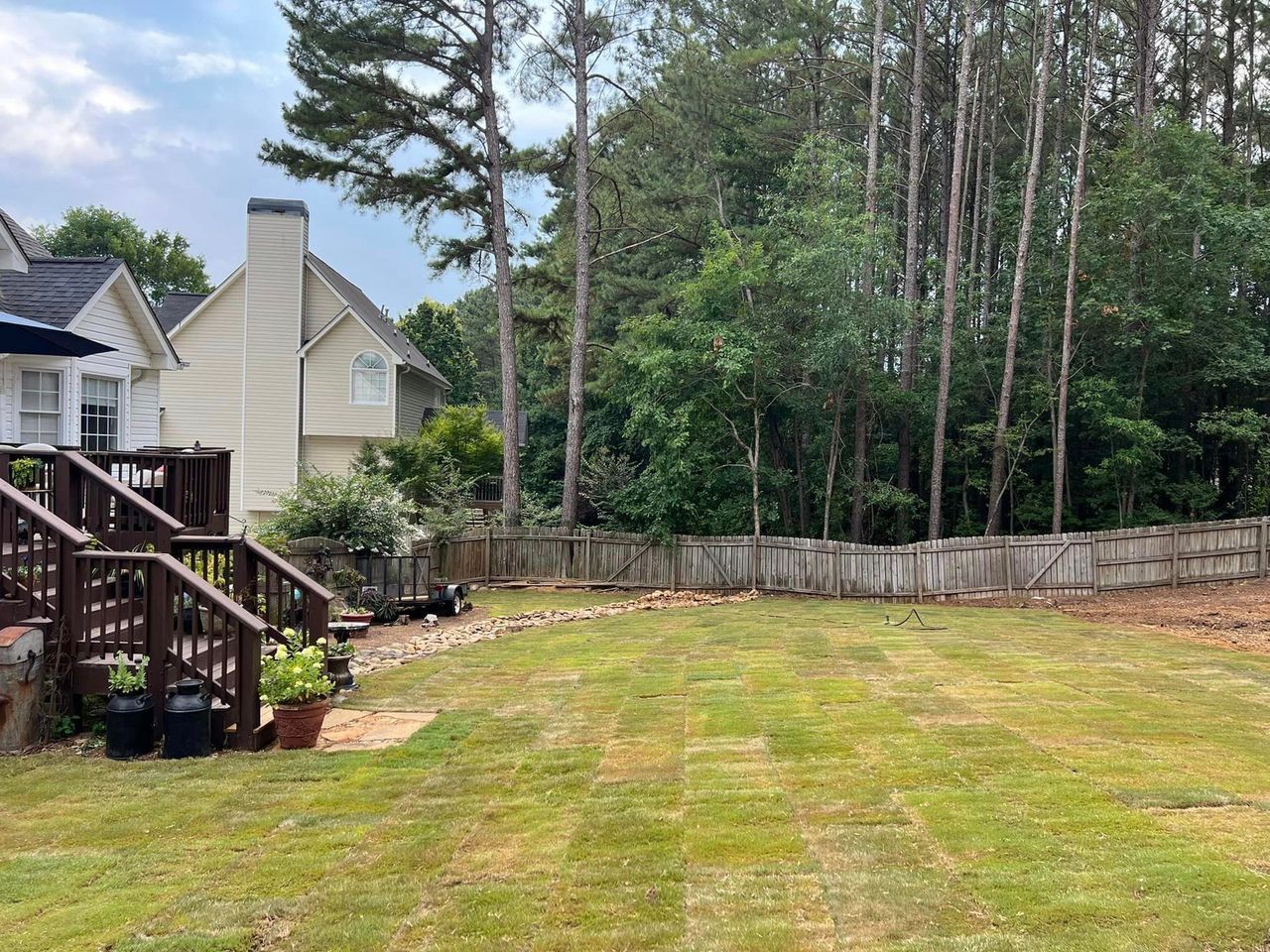 A backyard with a deck and a fence surrounded by trees.