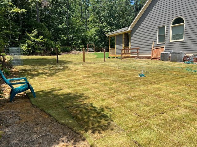 A large lawn with a blue chair in front of a house.