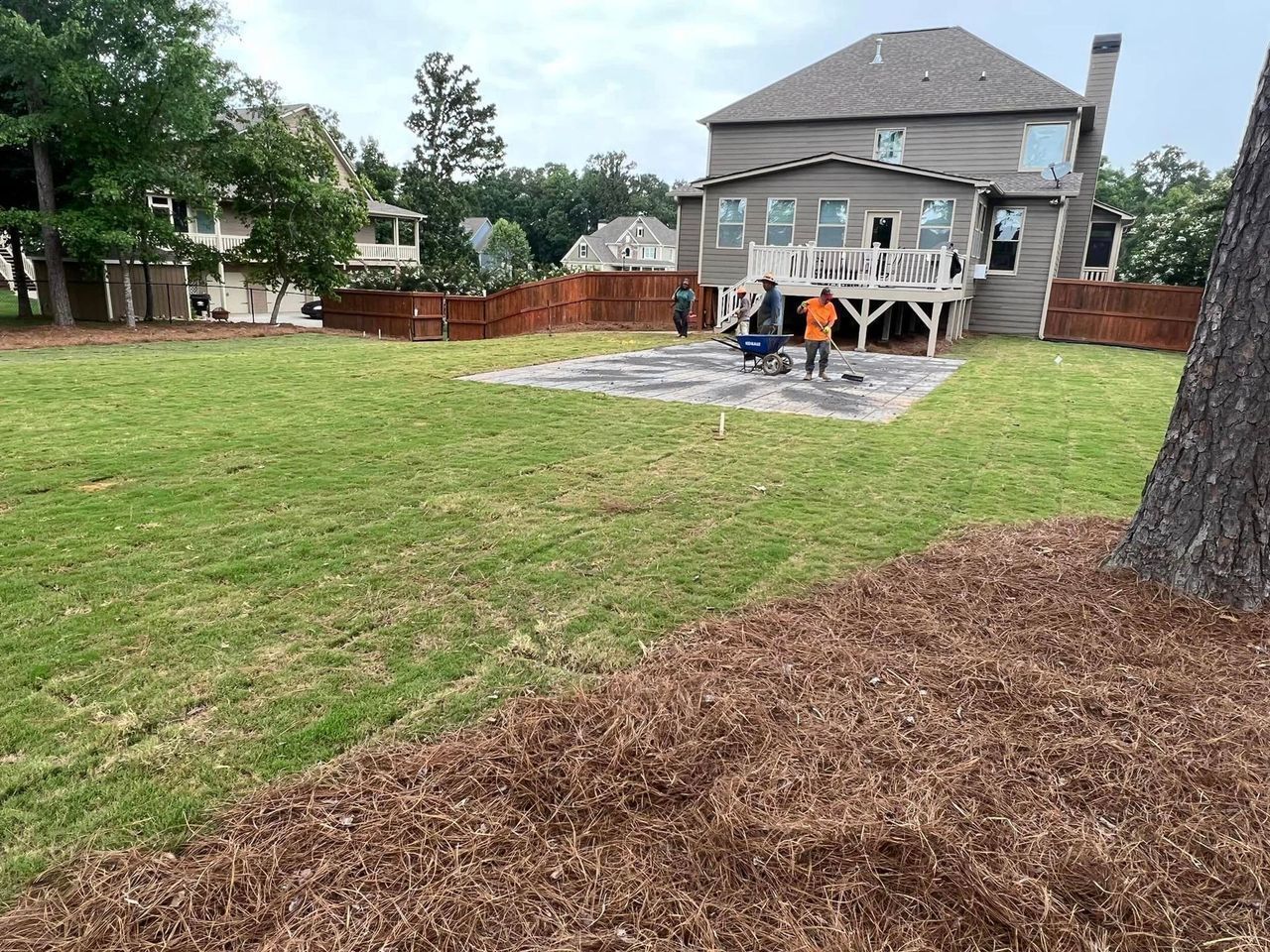 A large backyard with a house in the background and a lawn in the foreground.
