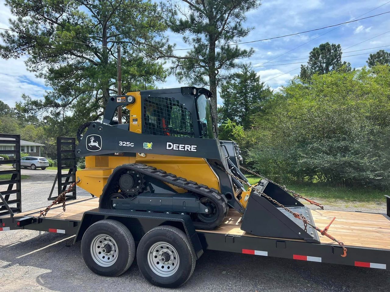 A yellow and black deere tractor is on a trailer.