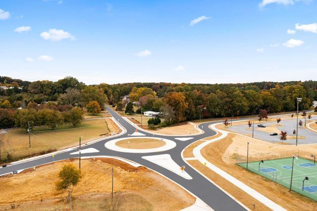 An aerial view of a roundabout with a tennis court in the background.