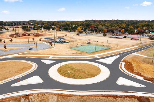 An aerial view of a roundabout with a tennis court in the background