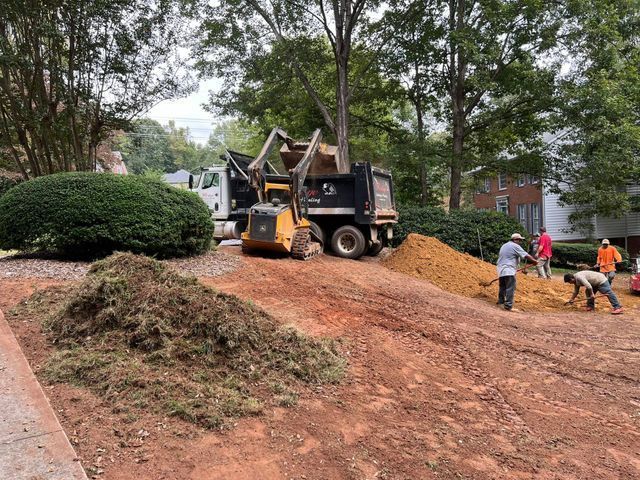 A dump truck is being loaded with dirt in a driveway.