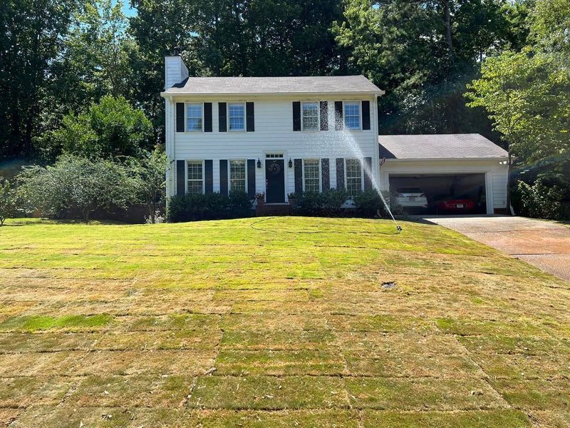 A white house with a large lawn in front of it.