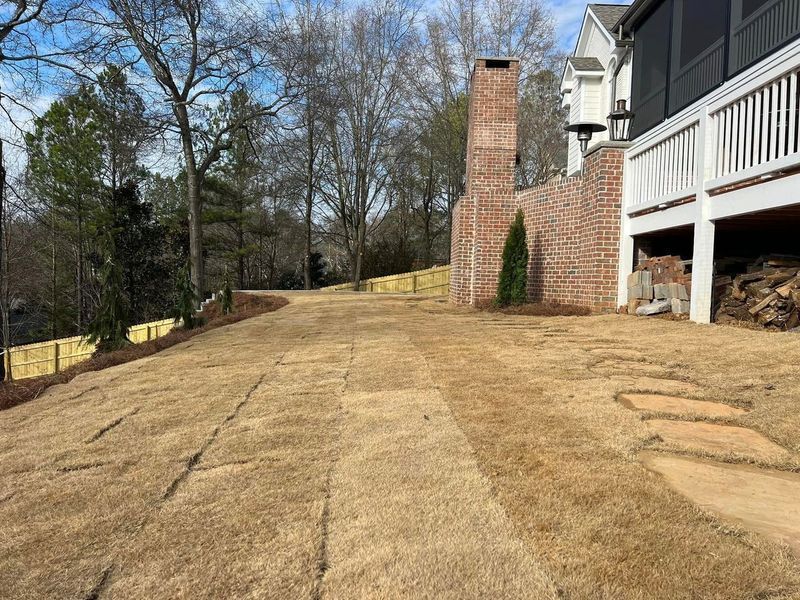 A driveway leading to a house with a brick chimney in the background.