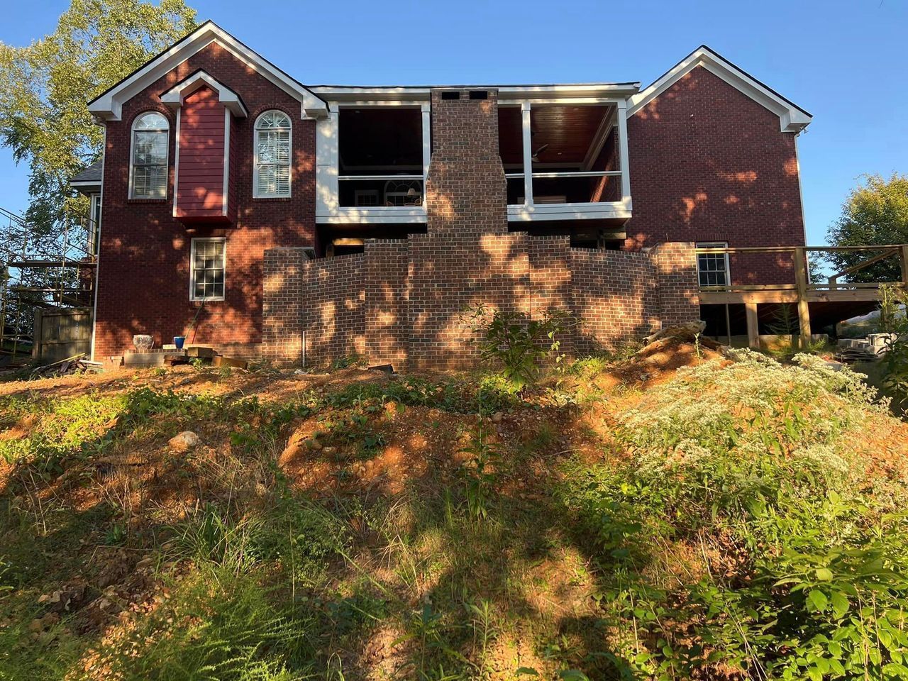 A red brick house is sitting on top of a grassy hill.