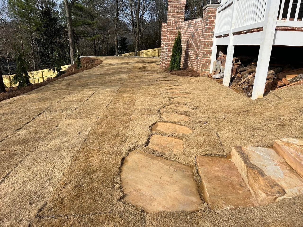 A stone walkway leading to a house with a brick building in the background.
