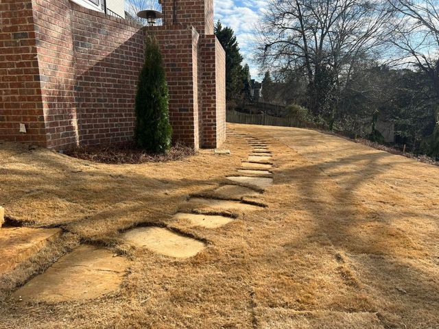 A stone walkway leading to a brick building on a hill.