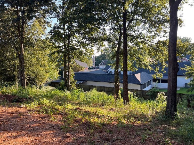 A house is visible through the trees in the background