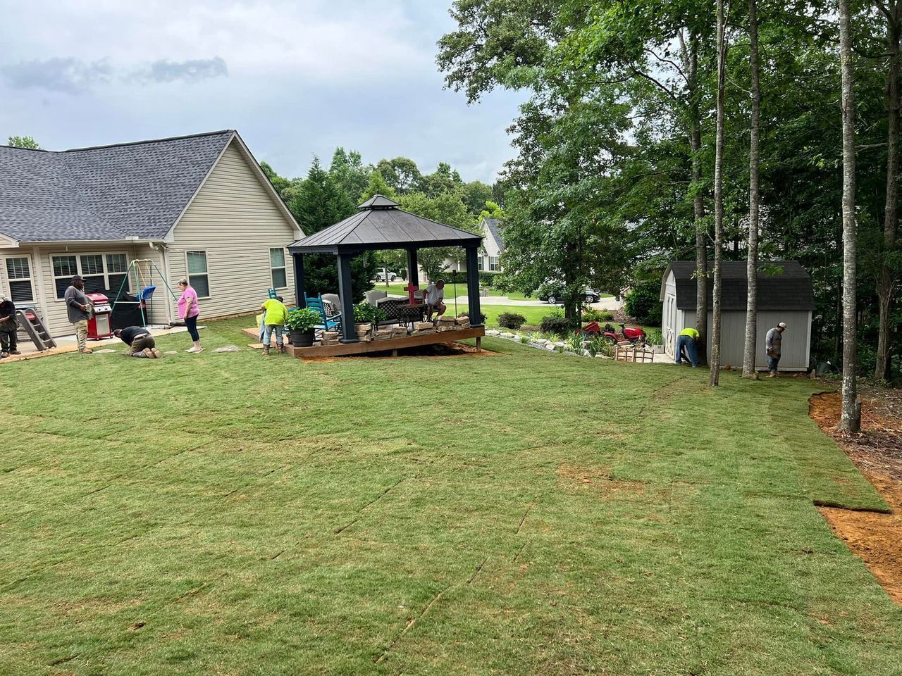 A gazebo is sitting on top of a lush green lawn in front of a house.