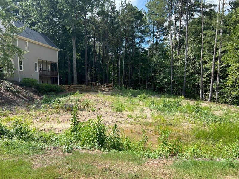 A house is sitting in the middle of a lush green field surrounded by trees.