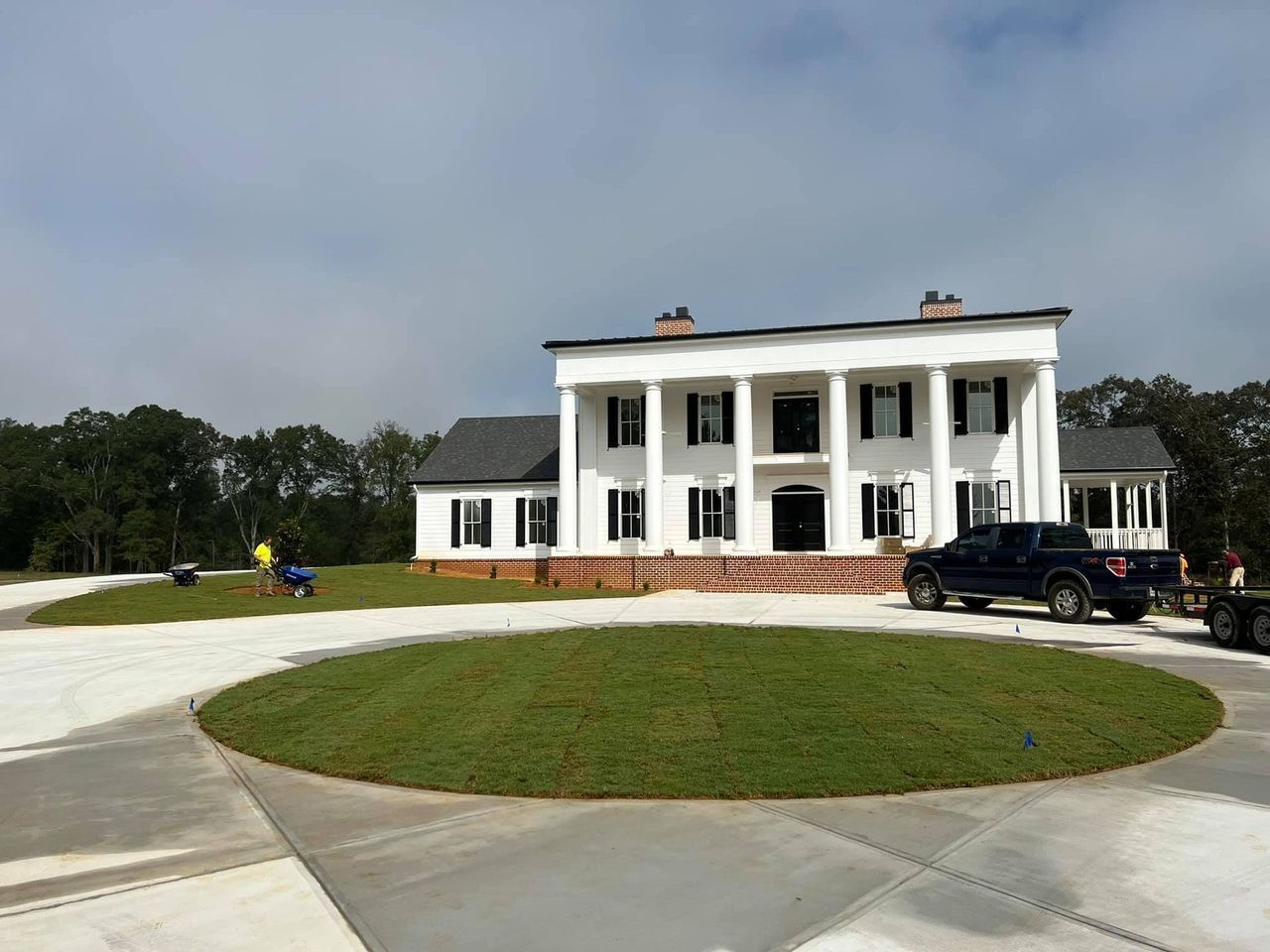A large white house with a truck parked in front of it