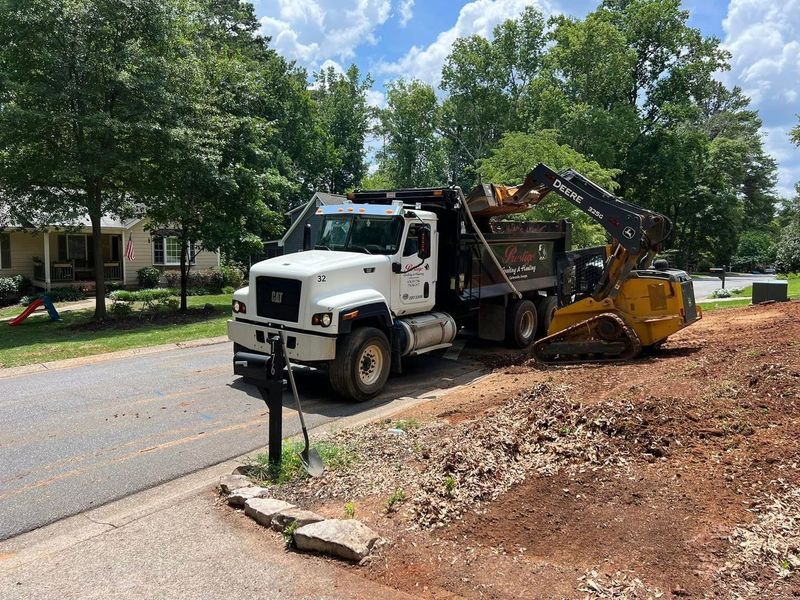 A dump truck is parked on the side of the road next to a bulldozer.